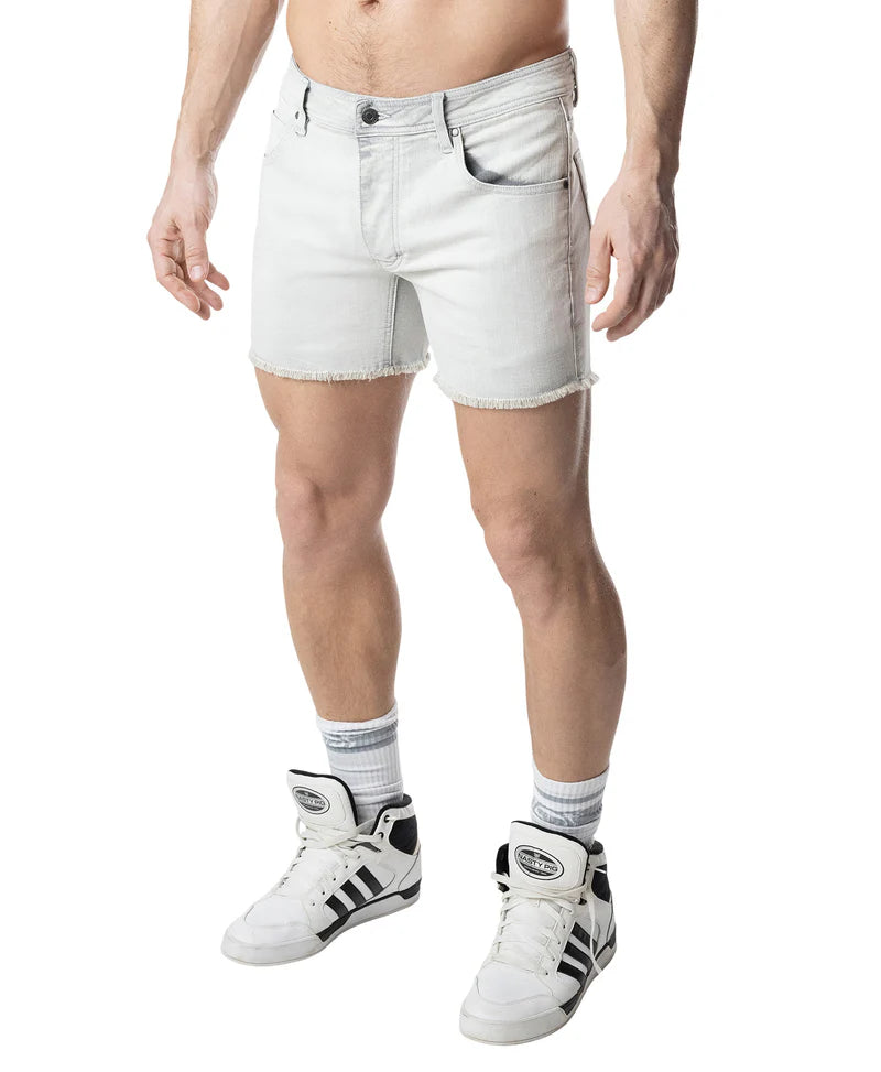 Person wearing white denim shorts and white sneakers with black stripes on a white background